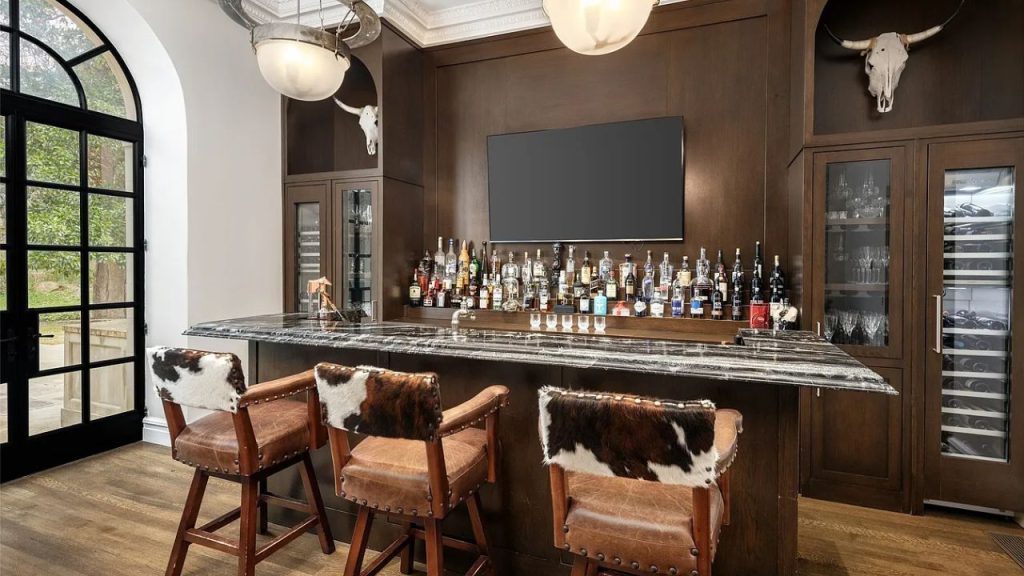 A rustic bar with marble counter, cowhide stools, and mounted steer skulls.