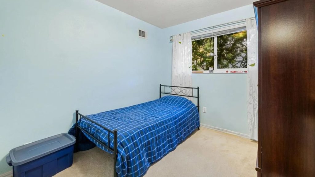 A simple bedroom with a blue checkered bed and wooden wardrobe.