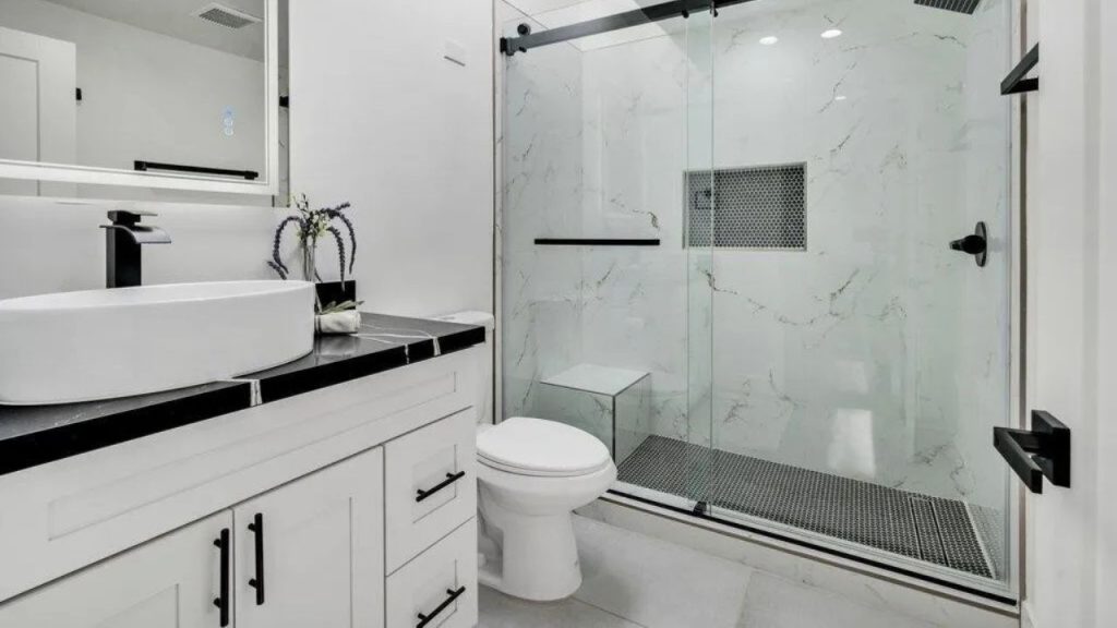 A modern bathroom with a glass shower, black countertop, and vessel sink.
