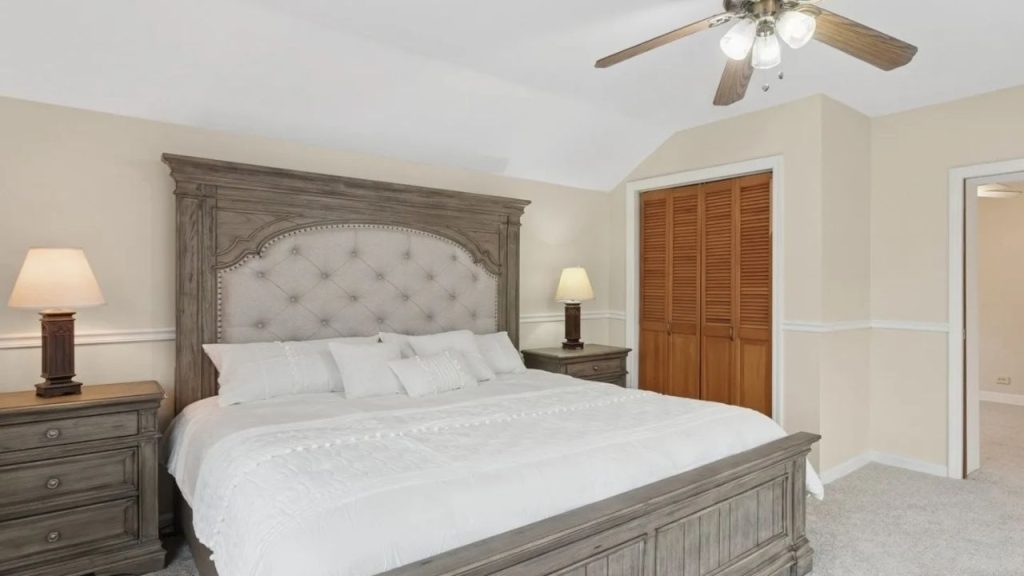Elegant bedroom with tufted headboard, wood furniture, and warm lighting.