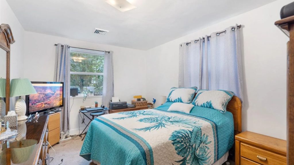 Cozy bedroom with teal bedding, light wood furniture, and natural light.