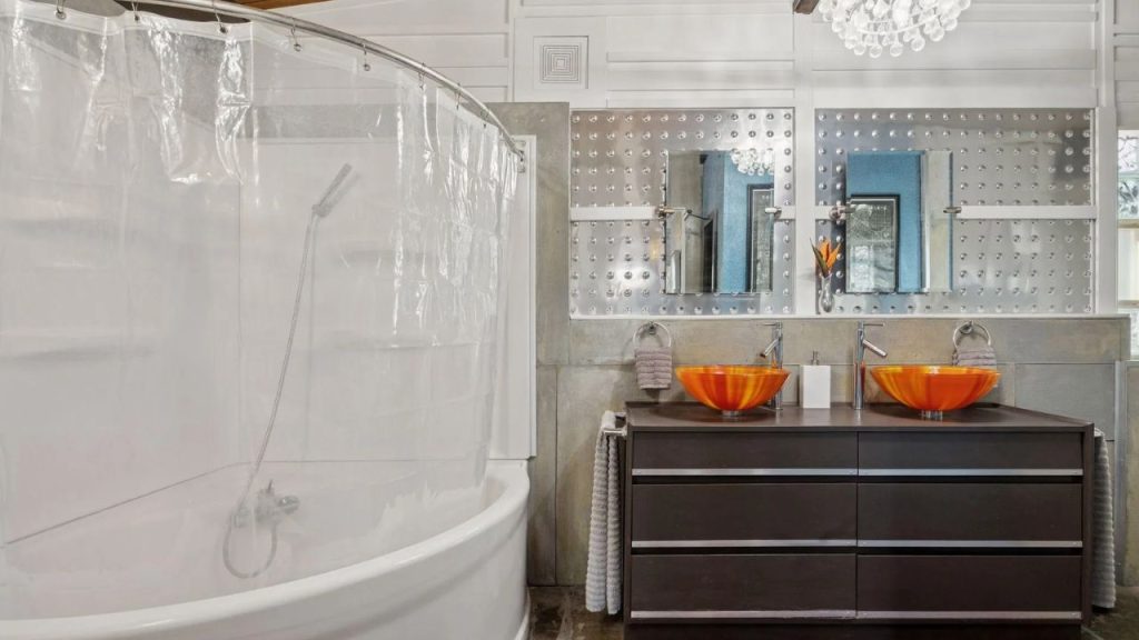 Stylish bathroom with orange sinks, metallic mirrors, and curved tub.