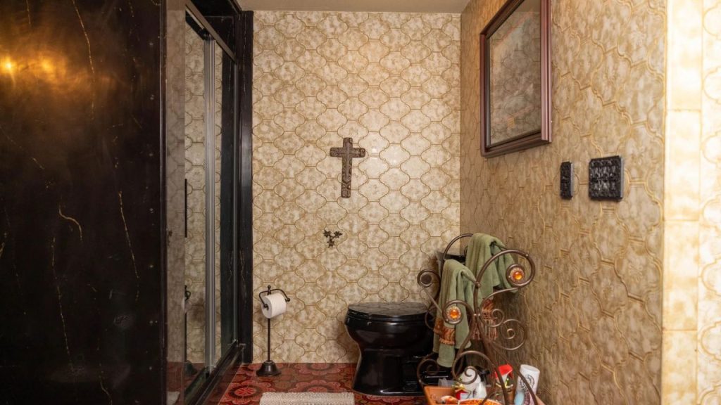 Vintage-style bathroom with warm-toned tiles, black fixtures, and rustic decor.