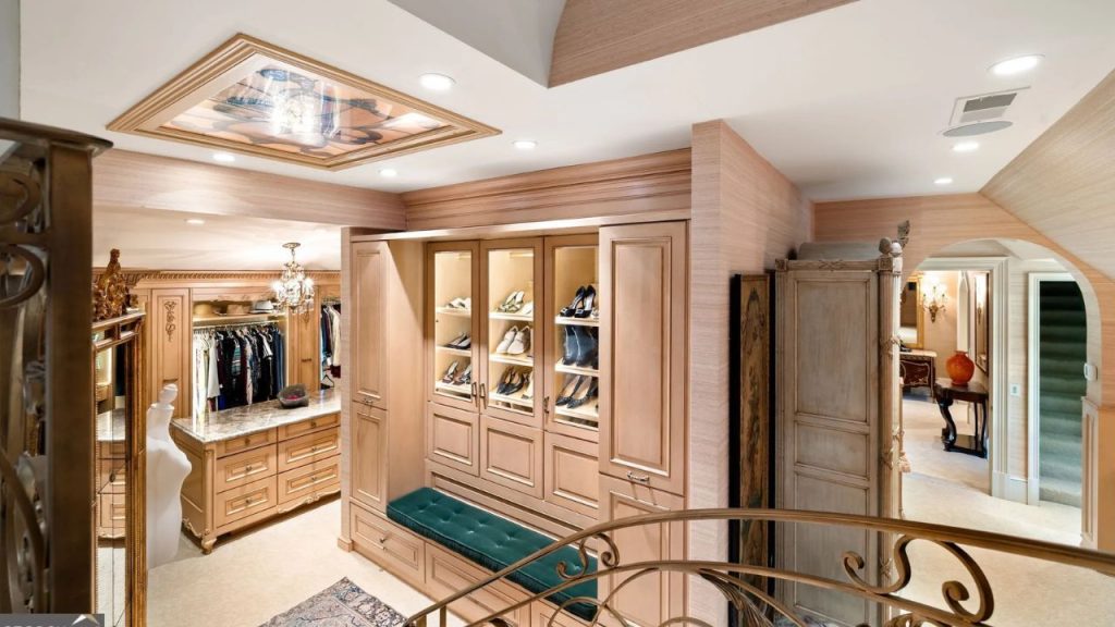 Luxurious walk-in closet with wood cabinetry, shoe display, and chandelier.