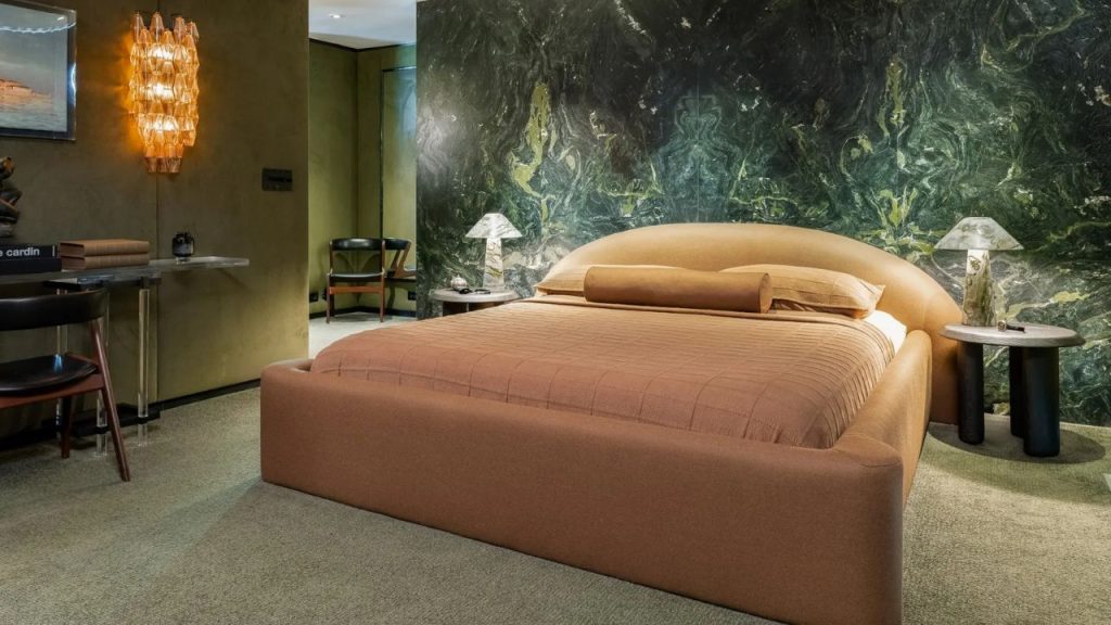 Earth-toned bedroom with a rounded bed frame and bold green marble accent wall.