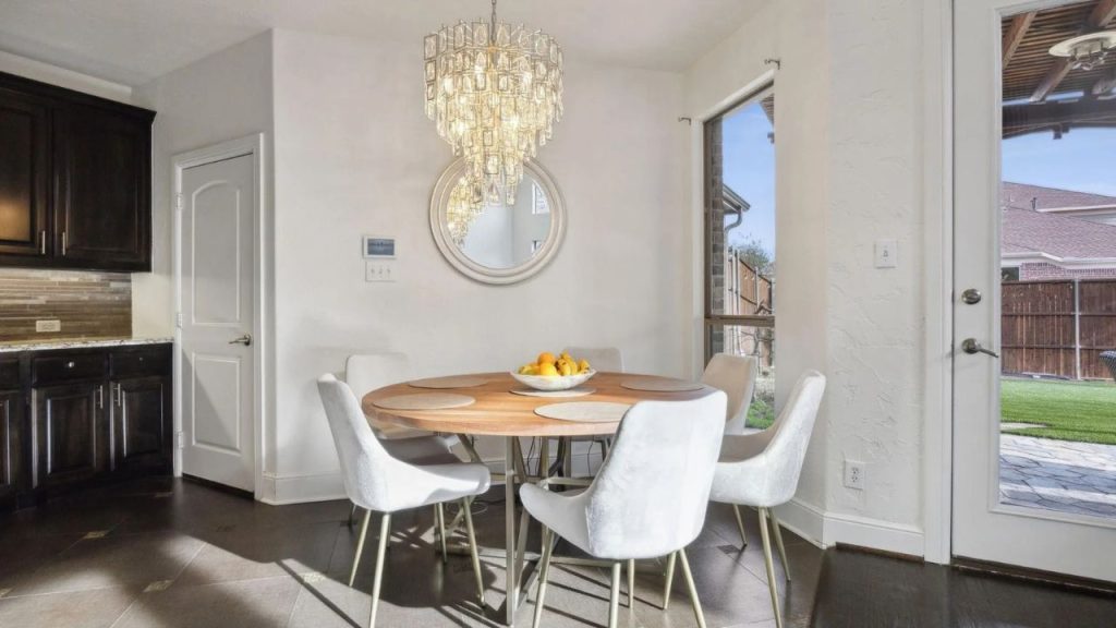 Chic breakfast nook with a round table, white chairs, and sunny backyard view.