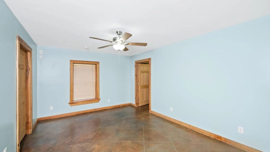 Peaceful bedroom with blue walls, wood trim, and a ceiling fan.
