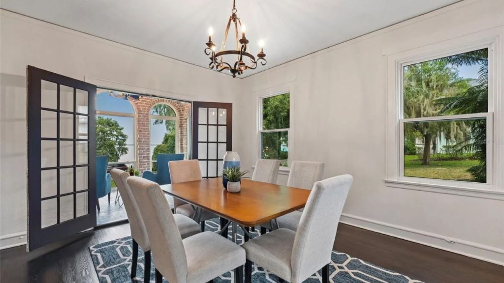 Dining room with French doors, wood table, and garden views.