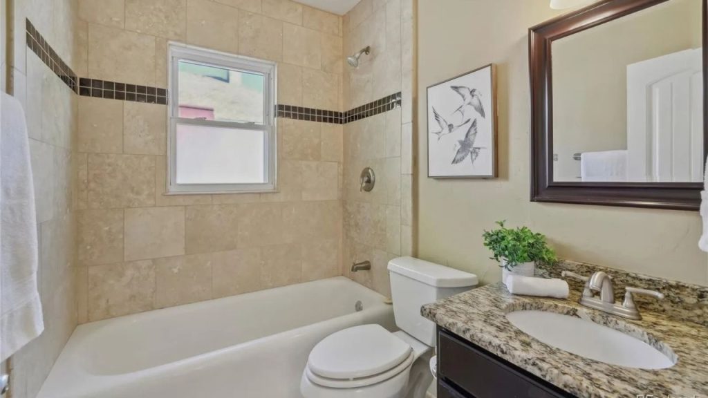 Cozy bathroom with tiled tub, granite counter, and soft natural light.