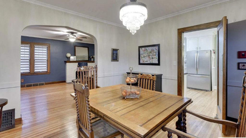 Dining room with wooden table and chandelier, connected to living room and kitchen.