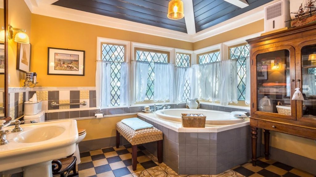 Bright corner bathroom with soaking tub, vintage charm, and lots of natural light.