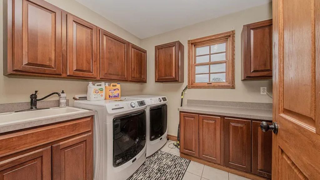 A cozy laundry room with wooden cabinets, washers, and a small window.
