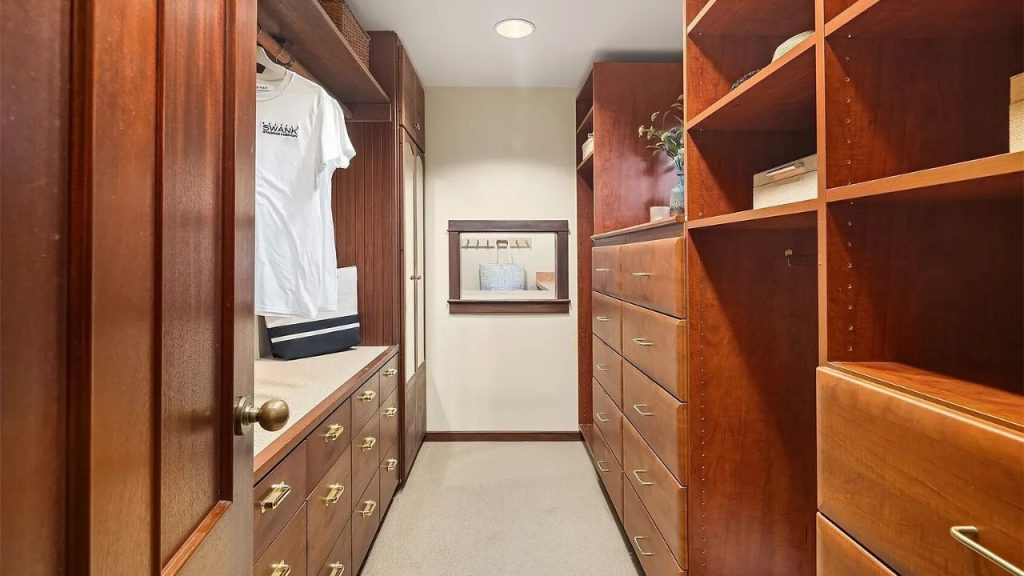 Wood-paneled walk-in closet with brass drawer pulls and open shelves.