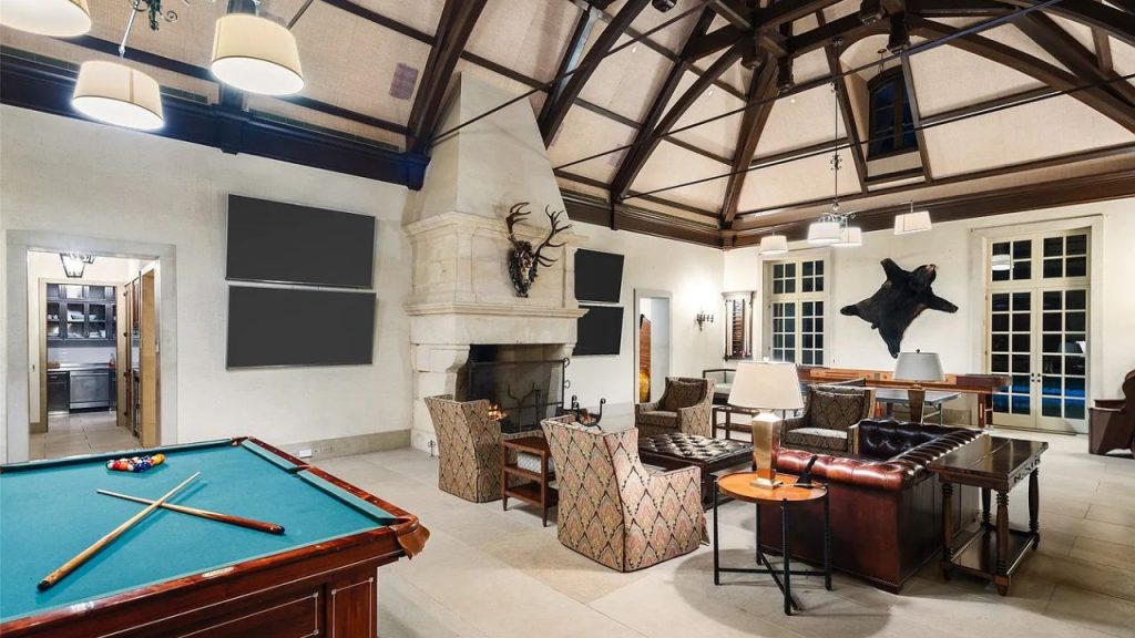 A cozy game room with a pool table, fireplace, and leather seating.