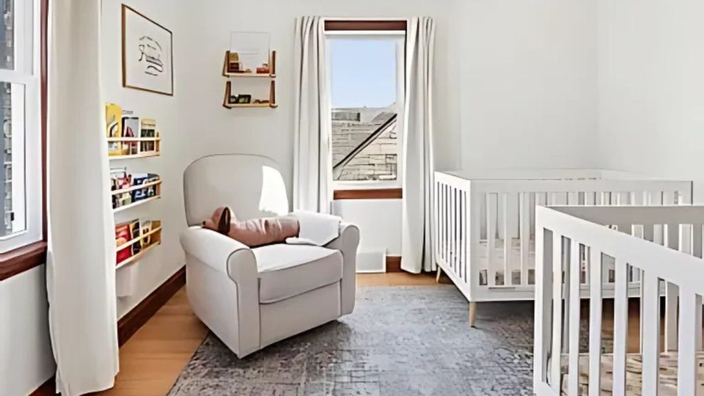 A charming nursery with white cribs, a plush armchair, and sunny windows.