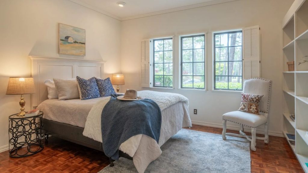 A peaceful bedroom with large windows and a cozy chair.