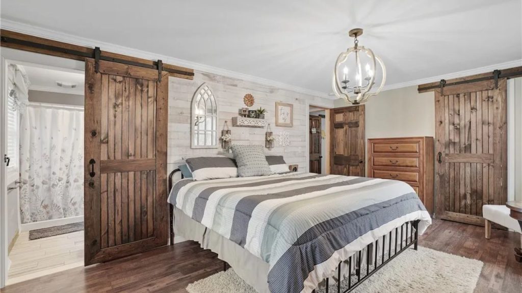 Farmhouse bedroom with barn doors and a cozy striped bedspread.