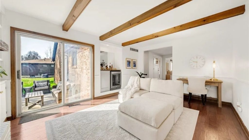 Bright living room with wood beams, sectional, and patio access.