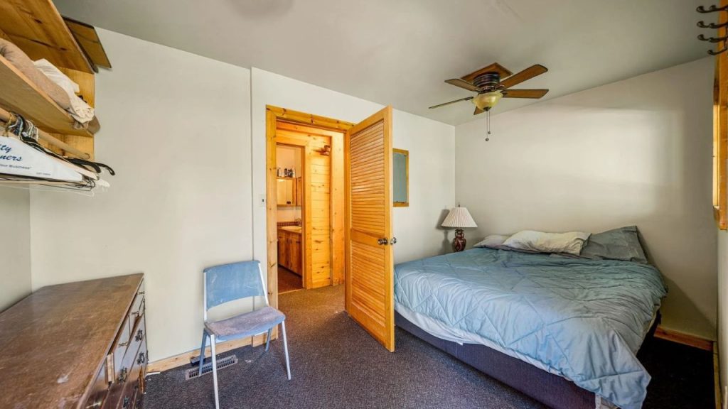 Cozy bedroom with wood accents, open closet shelving, and connected bathroom.