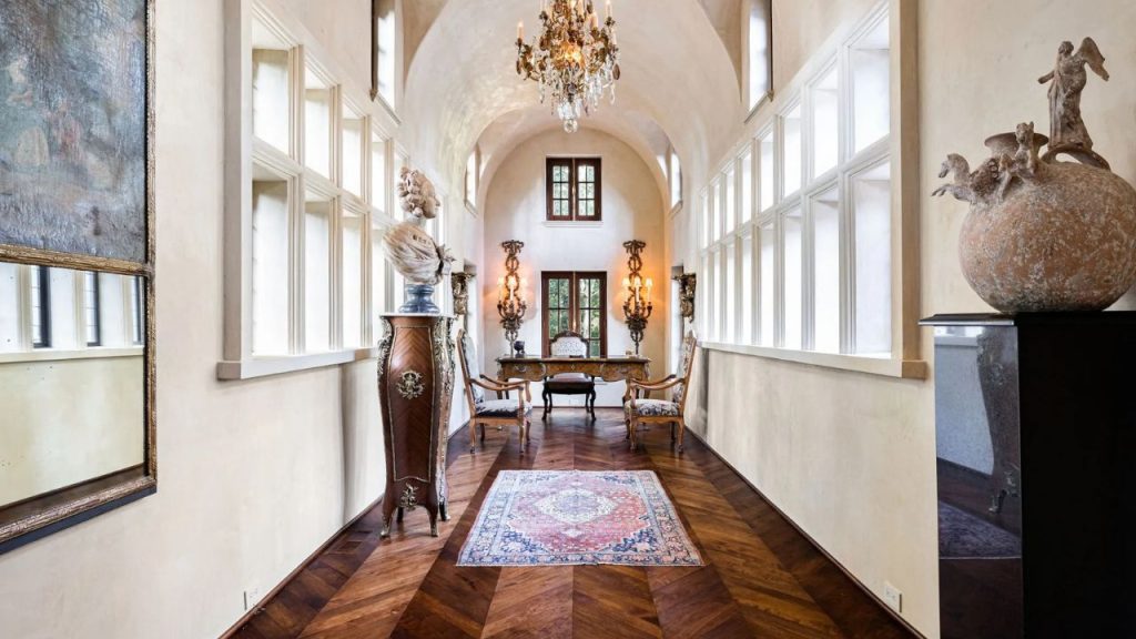 Elegant hallway with arched ceilings, antique furniture, and a chandelier.