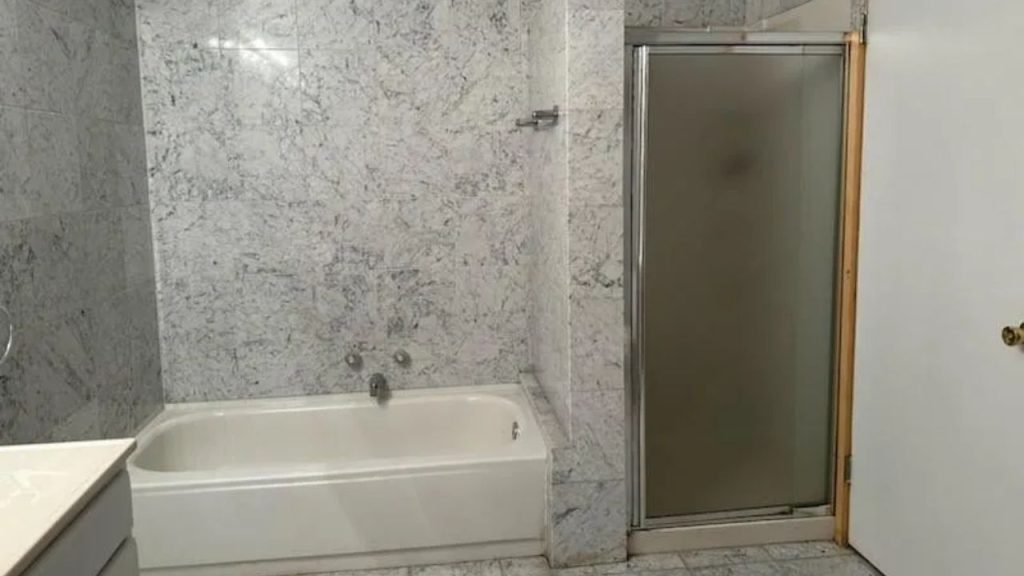 Marble bathroom with tub and frosted glass shower enclosure.
