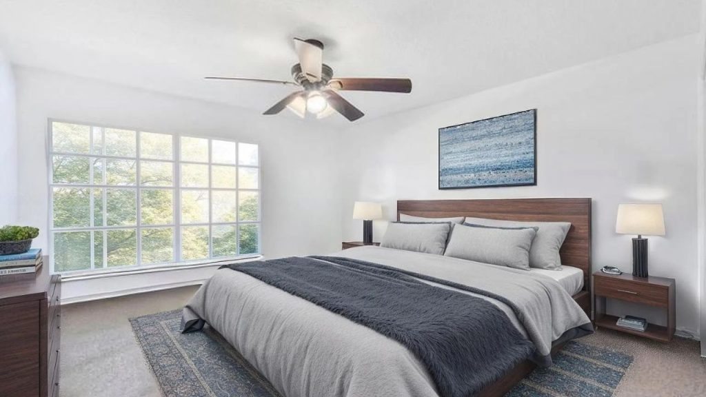 A peaceful bedroom with gray bedding, a large window, and abstract art.
