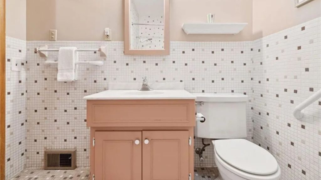 Charming bathroom with vintage tilework and soft peach vanity.