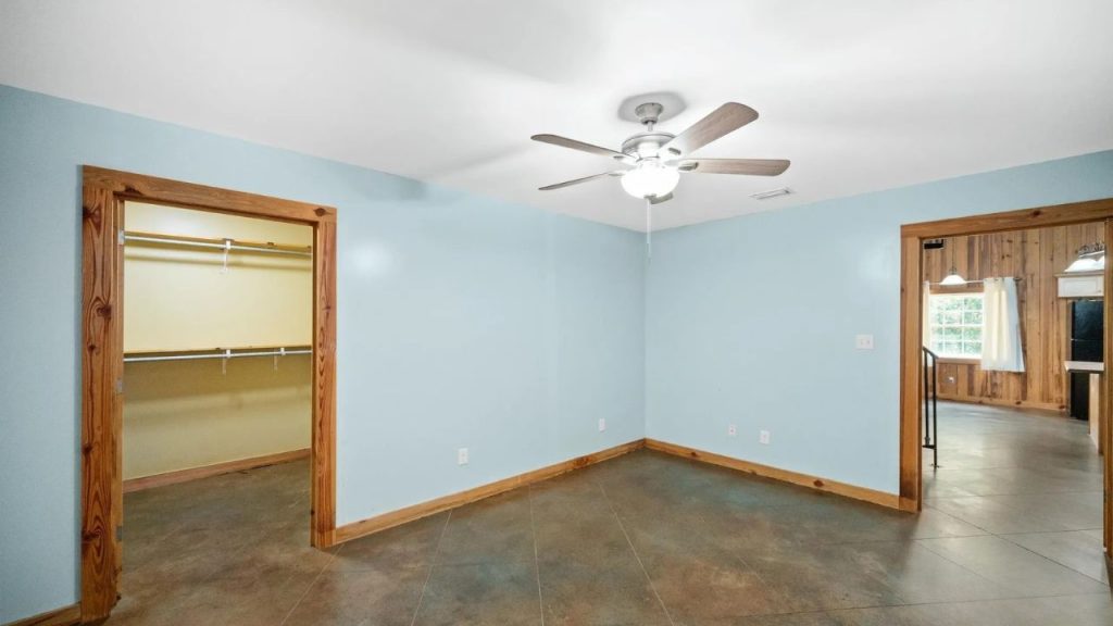 Bedroom with closet and view into a wood-paneled living space.