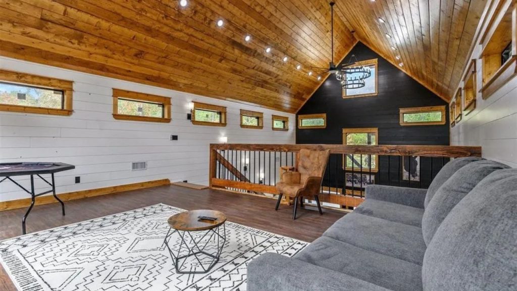 Inviting loft with wood ceiling, gray couch, and cozy decor.