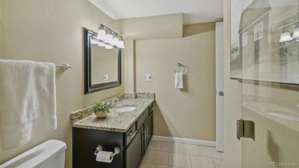 Neutral second bathroom with granite counter and warm lighting.