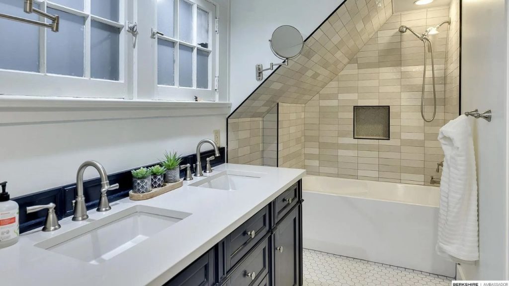 Double-sink bathroom with sloped ceiling over tiled shower.
