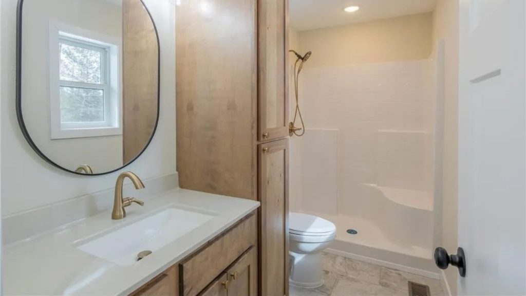 Bathroom with wood cabinets, brass faucet, and walk-in shower.