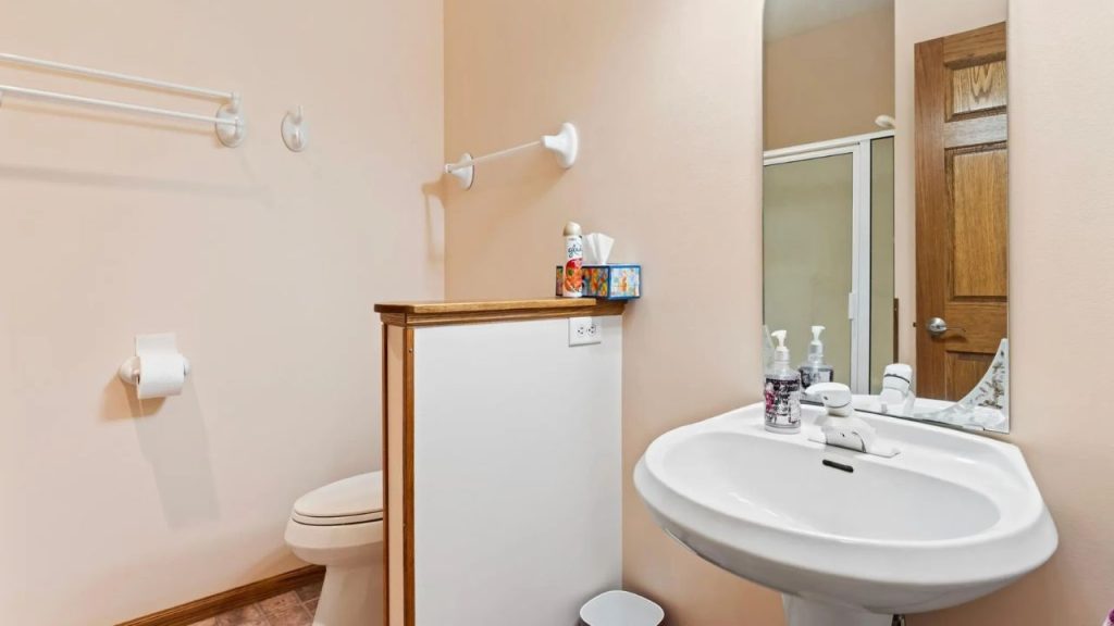 Simple bathroom with pedestal sink, mirror, and toilet.