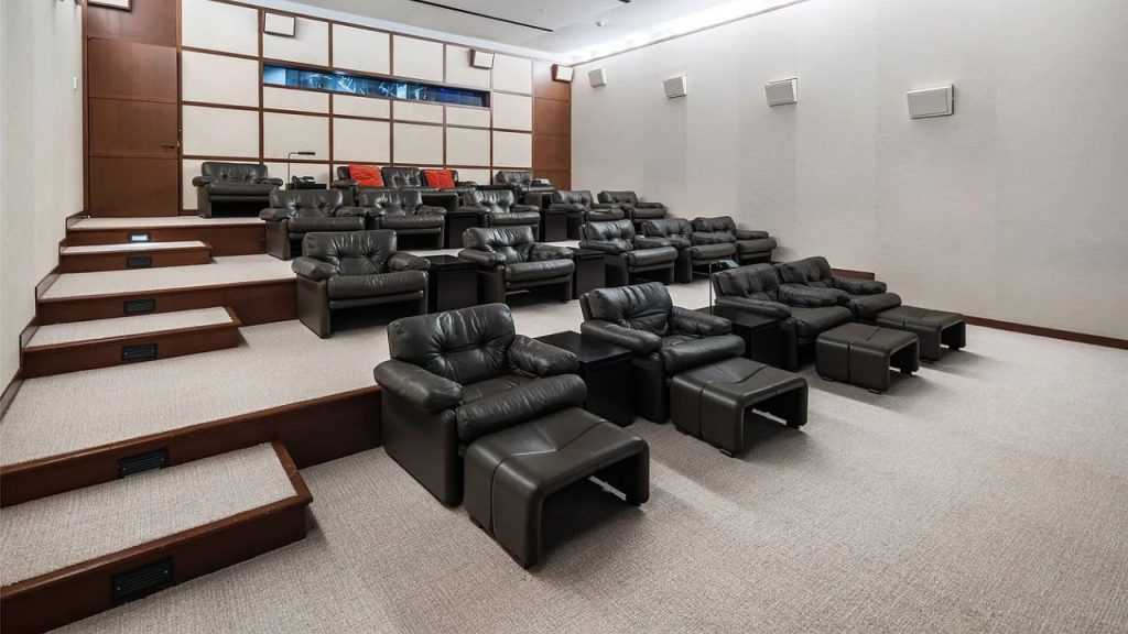 A cozy theater room with leather recliners and a large screen.