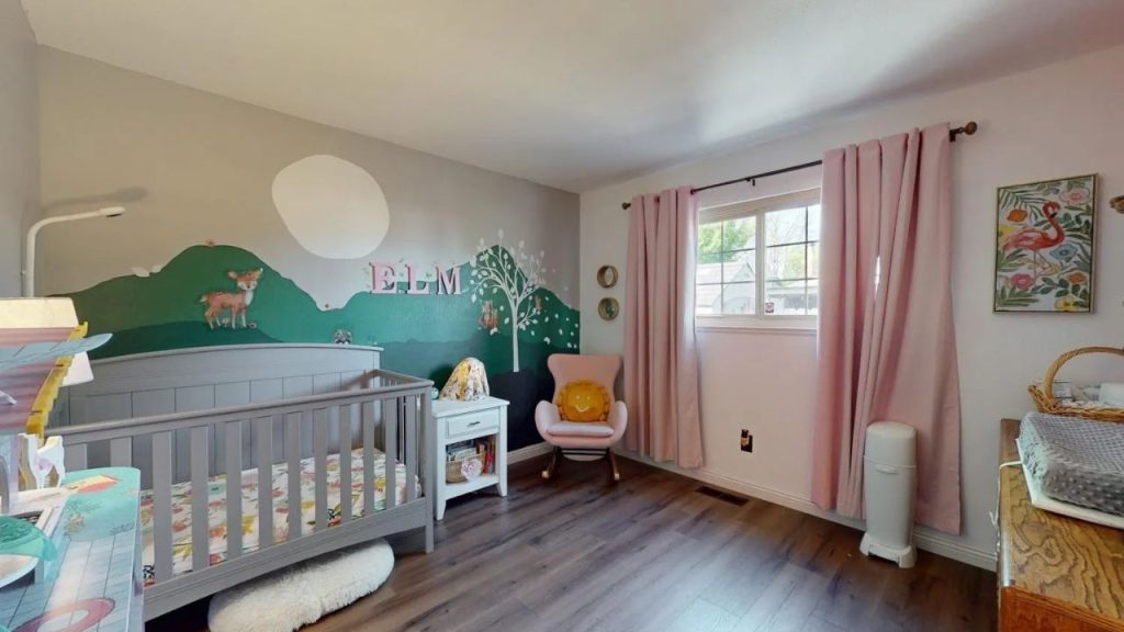 A cheerful nursery with a crib, deer mural, pink rocking chair, white dresser, and soft-curtained window.