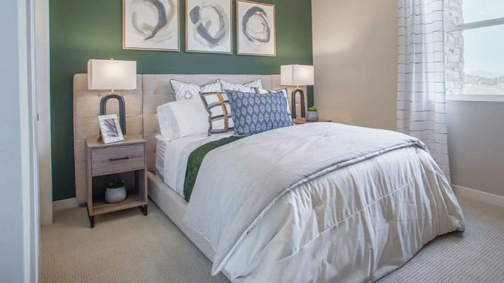 A serene guest bedroom with a green accent wall, white bed, patterned pillows, and modern nightstands with lamps.