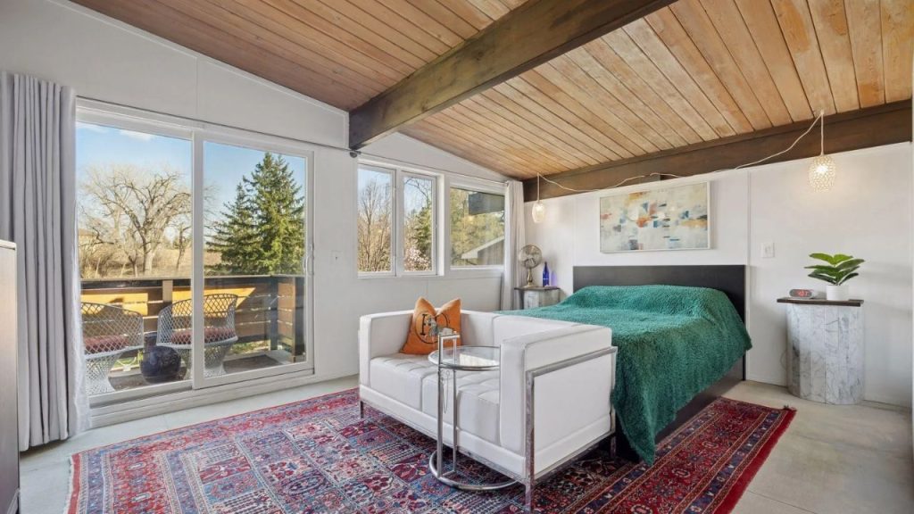 Bright bedroom with wood ceiling, balcony access, and Persian rug.
