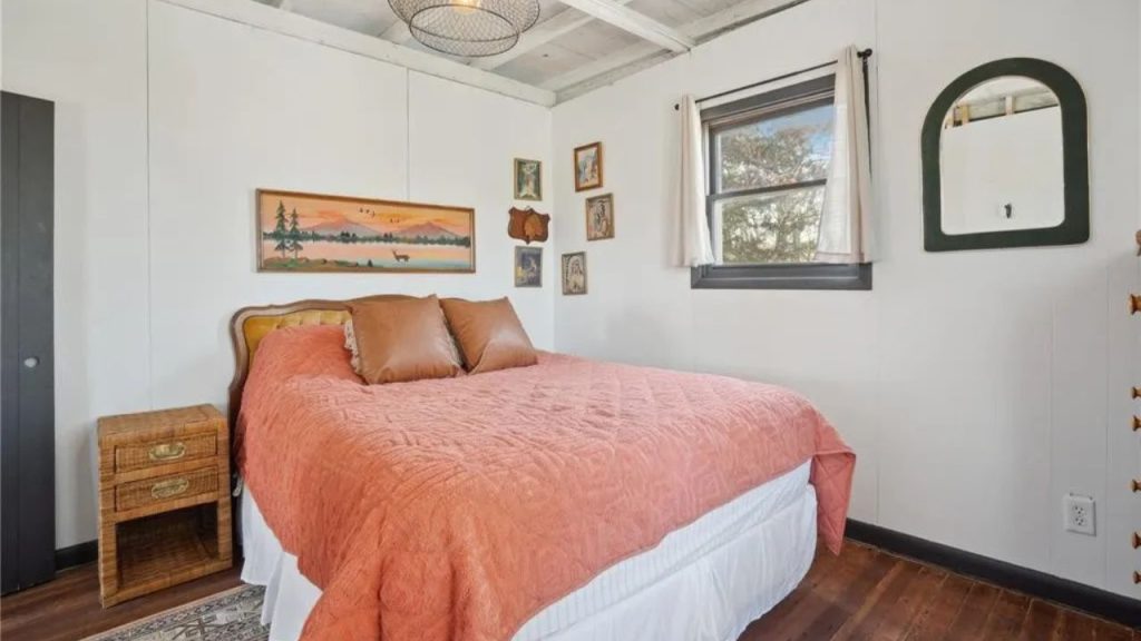 Rustic bedroom with burnt-orange bedding, a vintage headboard, and Western decor.
