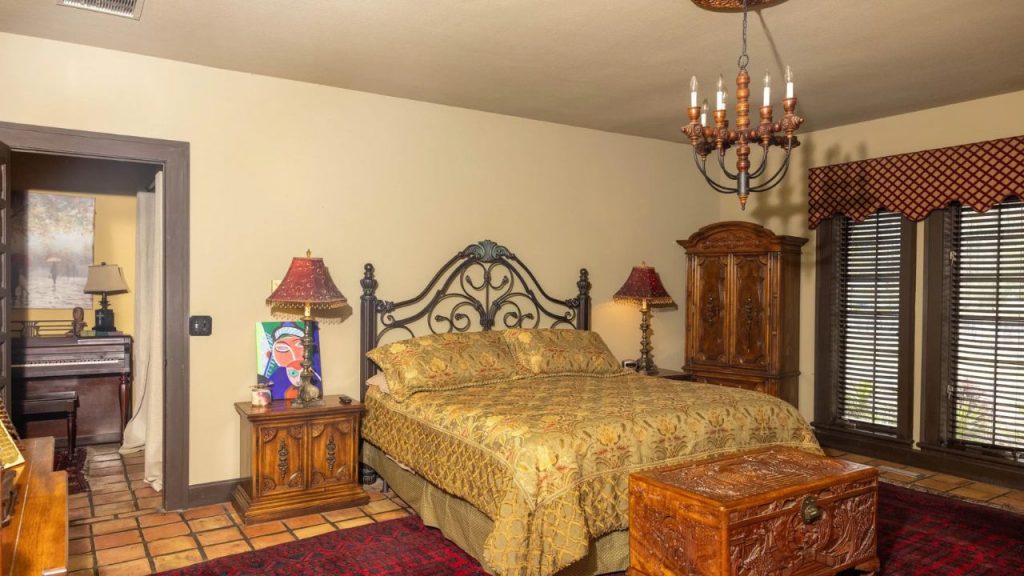 Cozy vintage bedroom with wrought-iron bed, wooden furniture, and warm lighting.