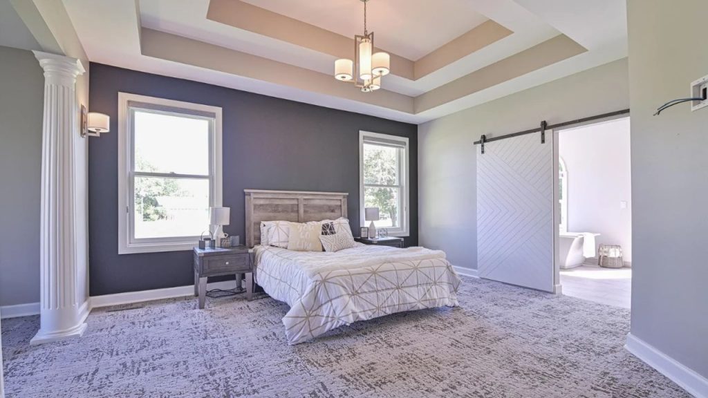 Bright bedroom with accent wall, coffered ceiling, and barn door leading to bathroom.