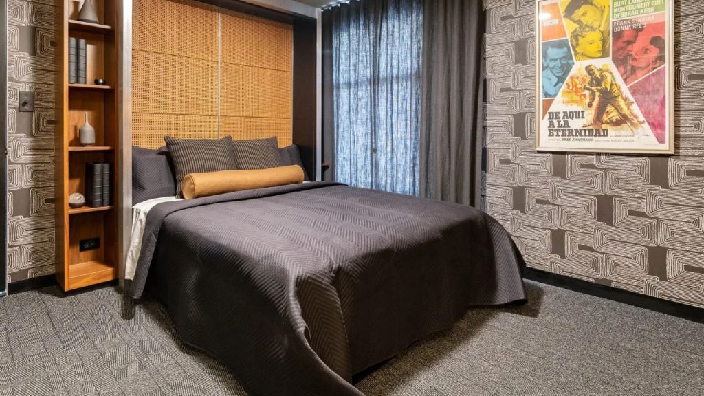 Stylish dark-toned bedroom with retro poster and bold wallpaper.