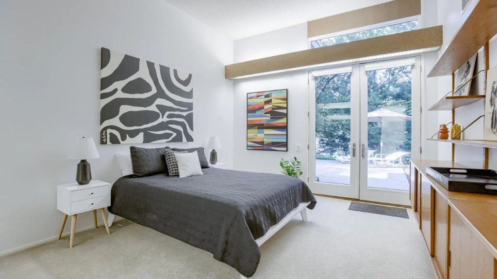 Bright bedroom with modern art, glass doors, and patio view.