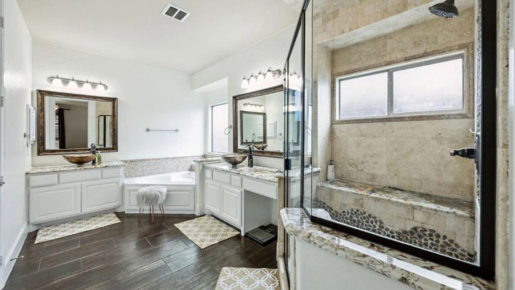 Spacious bathroom with stone-tiled shower, double vanities, and soaking tub.