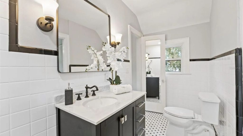 Black and white bathroom with marble vanity and orchid centerpiece.
