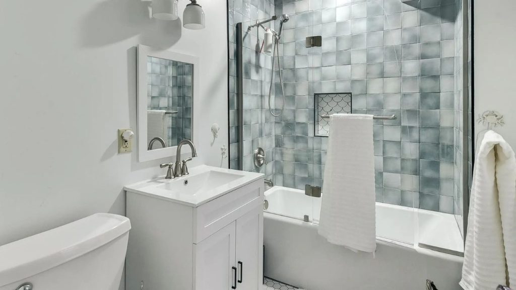 Calm blue-tiled bathroom with a white vanity and glass shower enclosure.