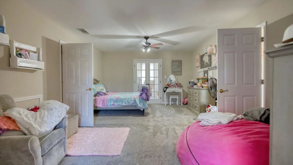 Cozy shared kids’ bedroom with twin and round beds, playful decor, and soft lighting.