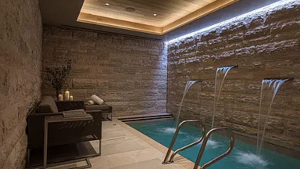 Tranquil indoor spa pool with stone walls and water features.