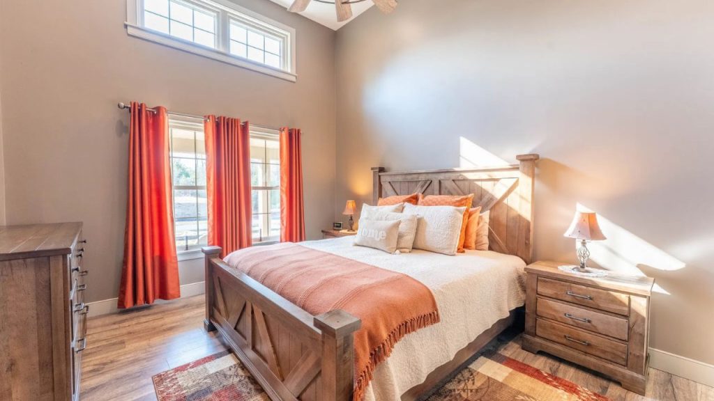 Warm rustic bedroom with wooden furniture, orange accents, and natural lighting.