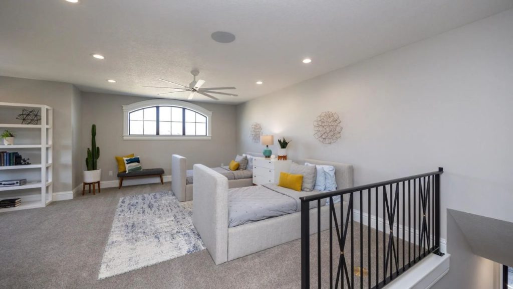 A spacious loft with cozy daybeds, large arched window, white bookshelf, and black railing, exuding a modern and inviting feel.