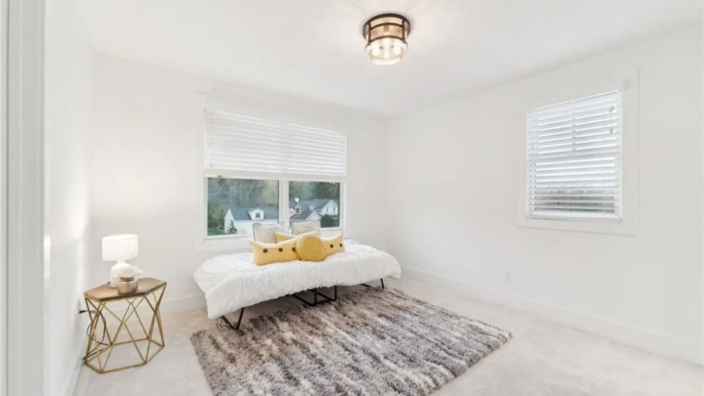 A bright guest room with a daybed, gold table, and large windows.